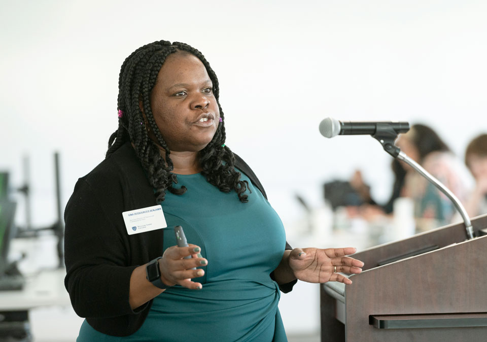 Black woman in green dress speaking at podium