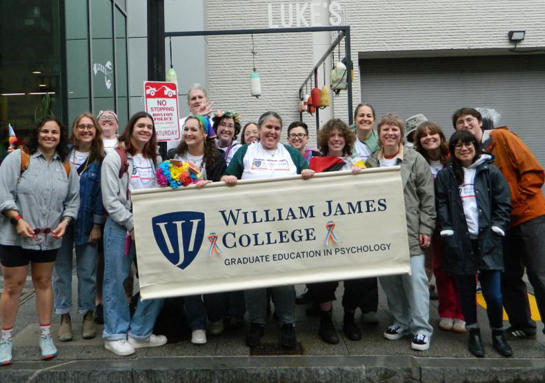Group of adults outside, in the rain, in front of a building and holding a large banner