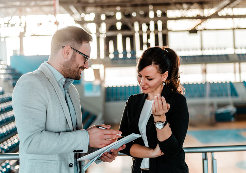 Admissions Two adults talking with gym behind them