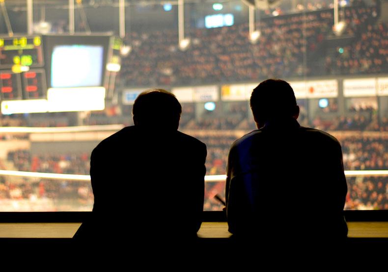 Curriculum Two men silhoetted with sports arena behind them