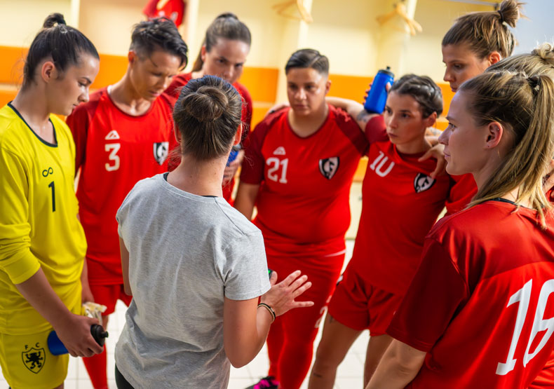 Program Overview group of girls in athletic shirts huddled around coach