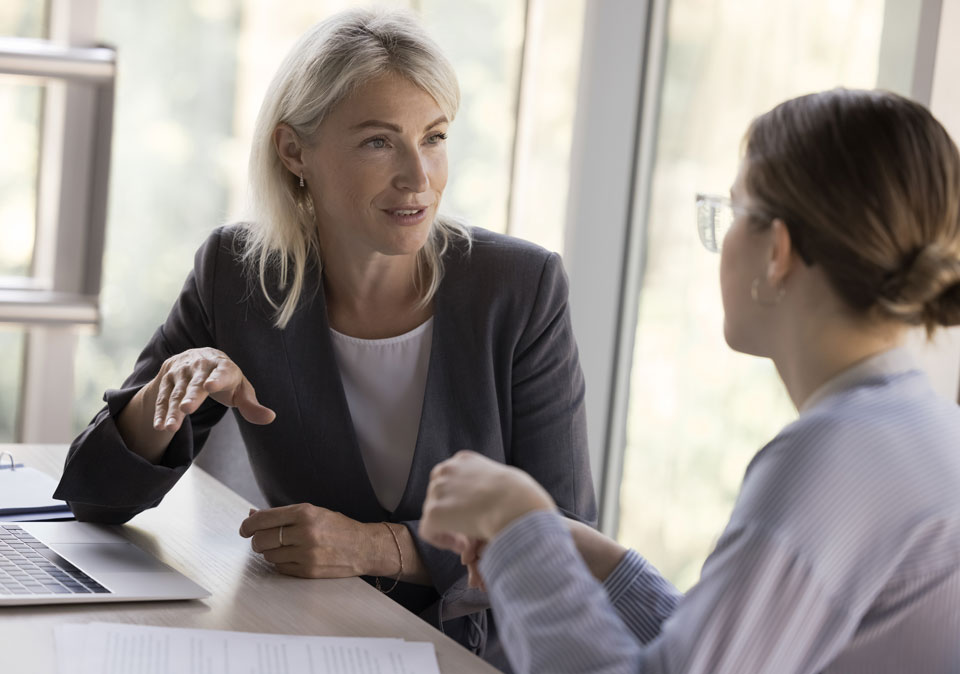 Professional woman sitting at a table talking to younger woman