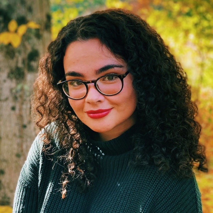 Olivia Geiger Portrait photo of woman with dark hair and glasses in outdoor scene