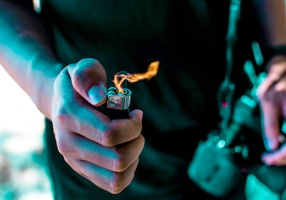 image of male hand holding a lighter with flame