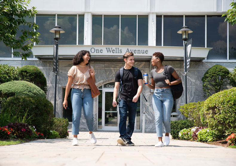 three students walking in front of building
