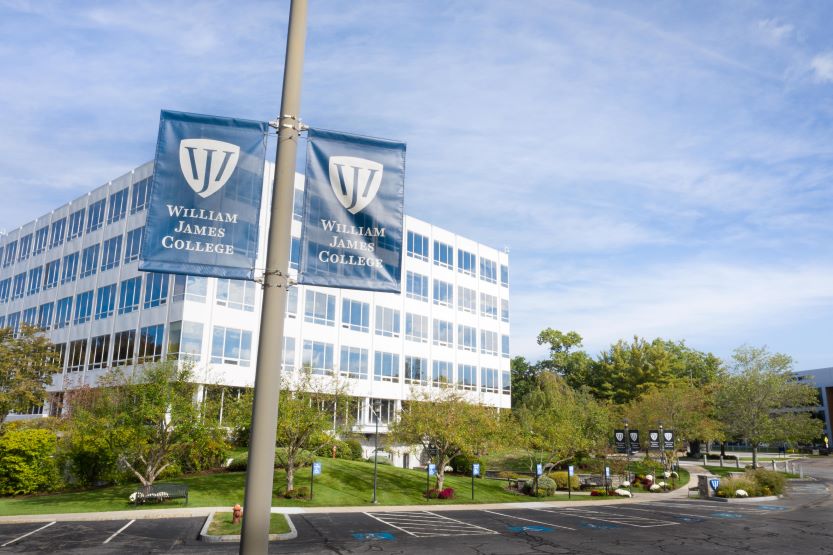 Photo of William James College banners in front of the campus building