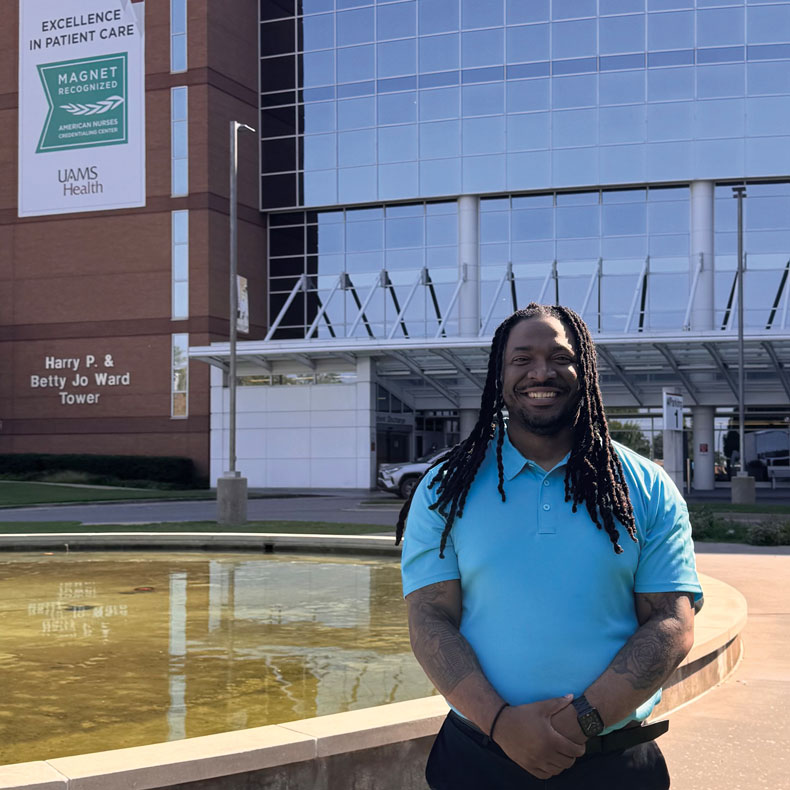 Joshua Finney Man standing in front of a hospital with reflecting pool