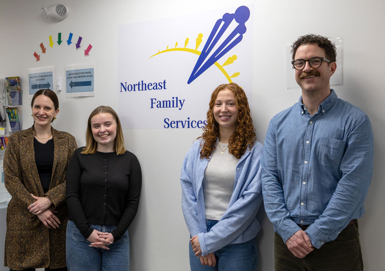 group of adults standing in front of company logo