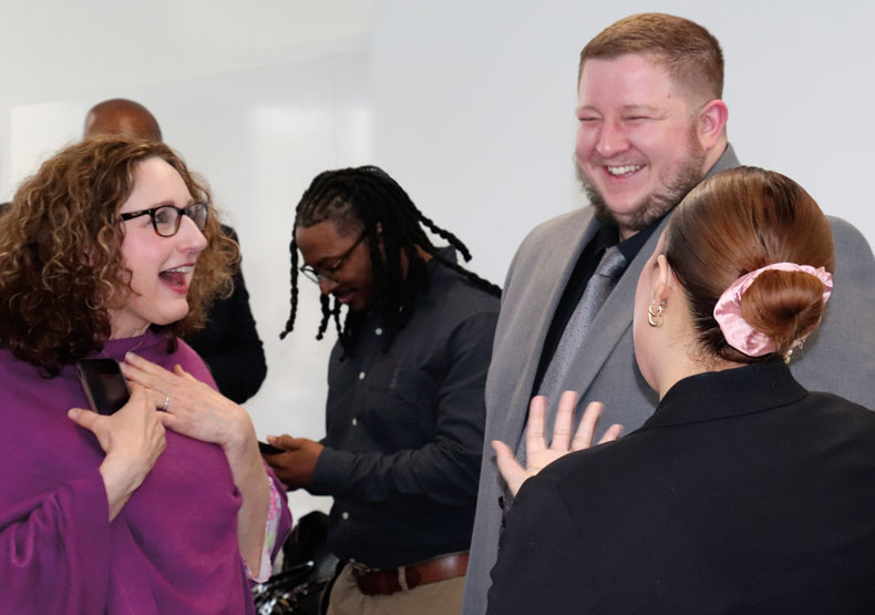 small group of adults talking and laughing in a classroom setting