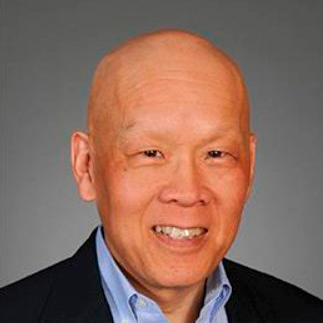portrait of asian adult male with no hair, and in a dark jacket with neutral background