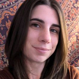 close-up photo of smiling woman with straight brown hair and a decorative fabric behind her